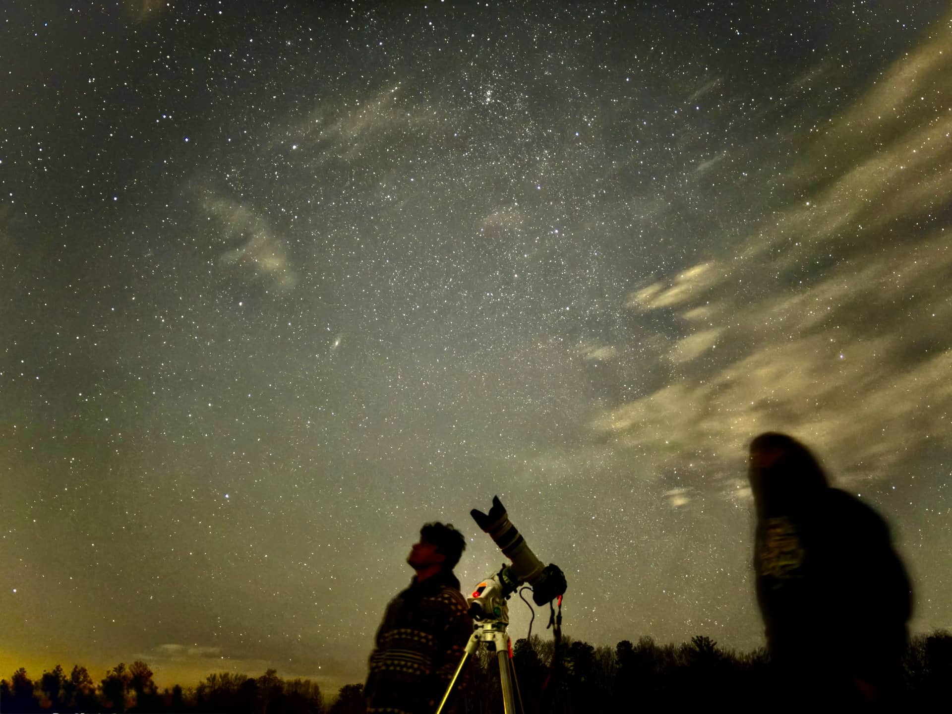 Two figures beneath a starry sky, a camera on a star tracker between them